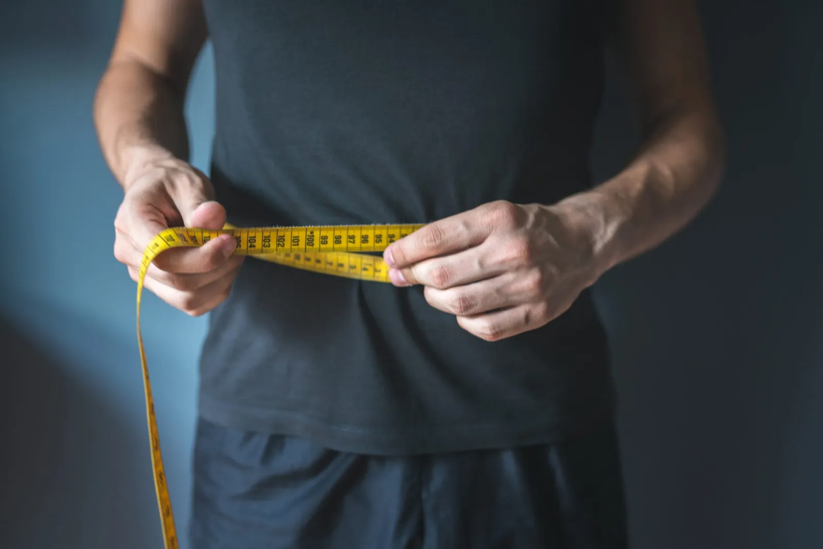 man measuring waist before medical weight loss